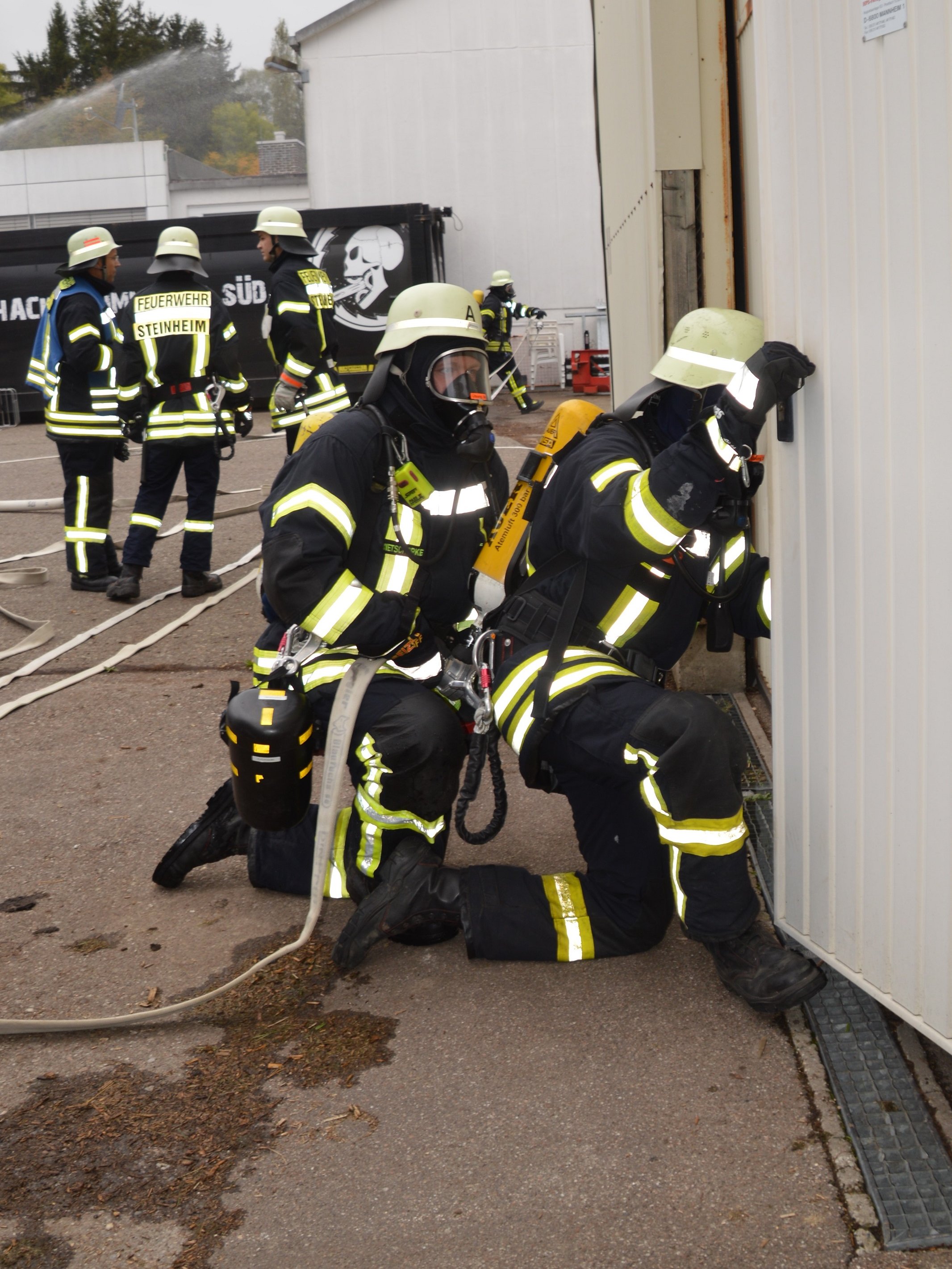 Zwei Feuerwehrleute ausgerüstet mit Atemschutzgräten gehen in die Lagerhalle vor um nach Personen zu suchen.